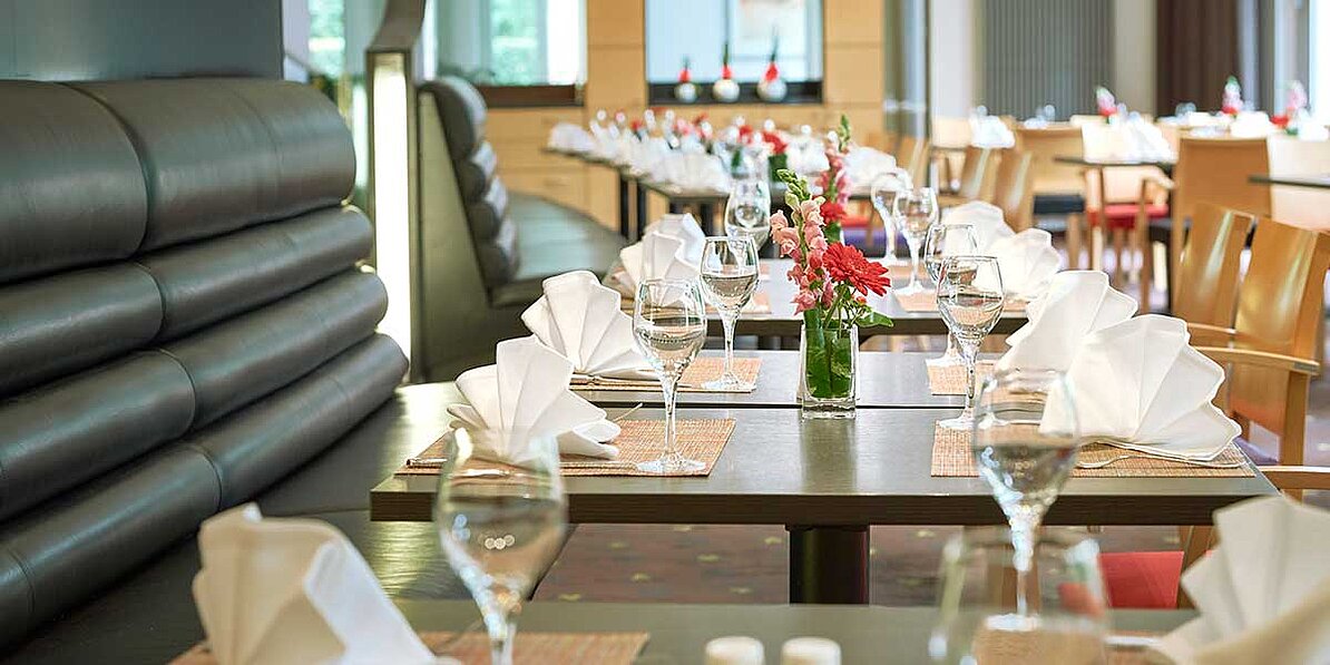 Das Bild zeigt mehrere elegant gedeckte Tische in einem Restaurant oder Hotel, die eine ruhige und einladende Atmosphäre ausstrahlen.